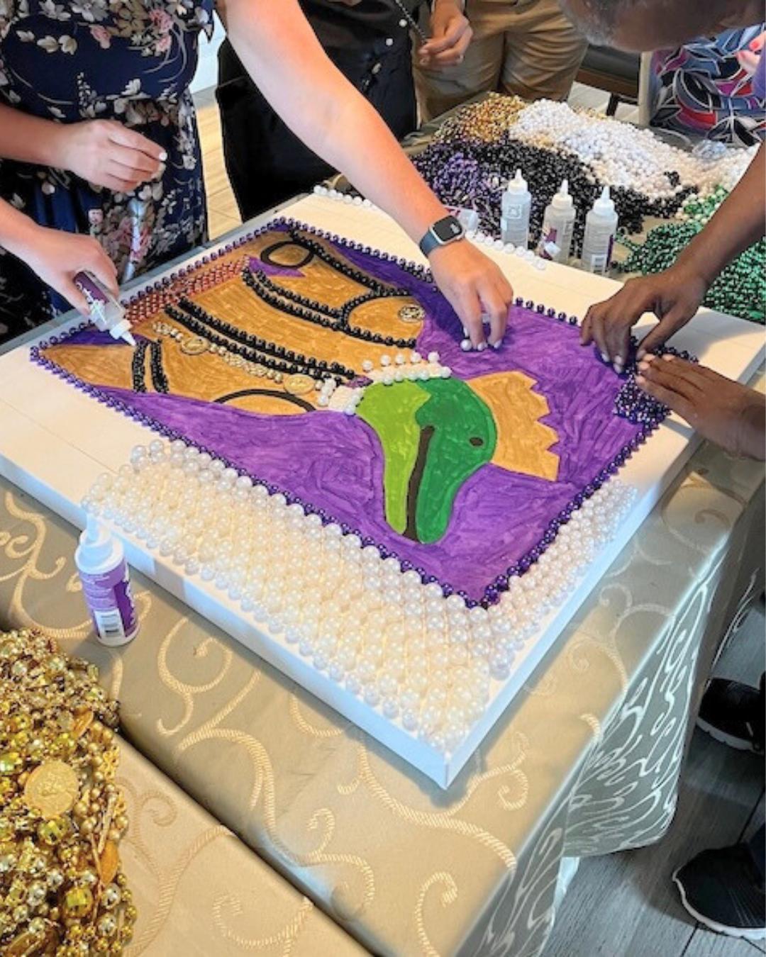 Corporate team building bead art workshop in New Orleans with participants creating a Mardi Gras–themed alligator design for The Royal Sonesta New Orleans, using recycled beads through ACCENT New Orleans DMC.