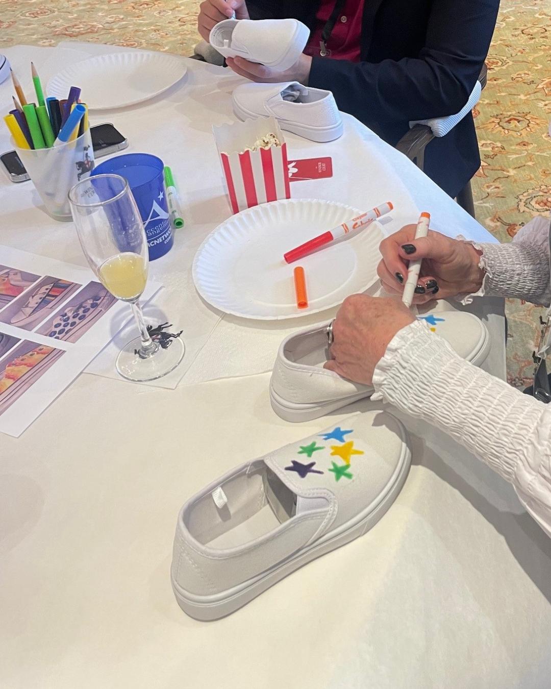 Corporate team members decorating shoes as part of a New Orleans giveback workshop where painted shoes are donated to local children.