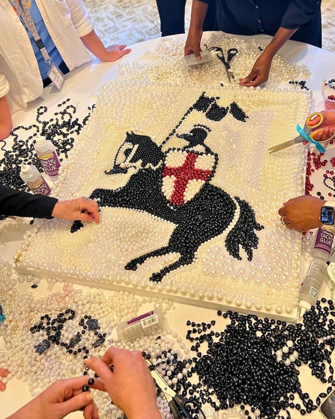 Corporate teams assembling the black, white, and red knight-themed bead art design of Windsor Court during a New Orleans giveback activity with ACCENT New Orleans DMC.