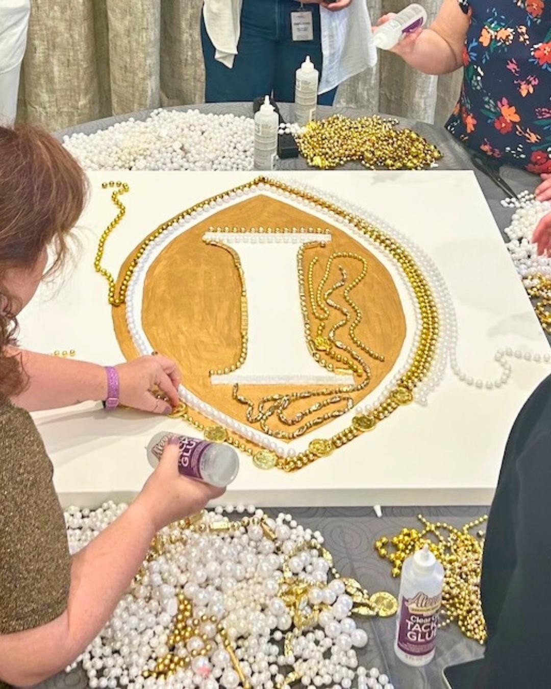 Corporate team building participants starting a gold and white bead art crest of the Intercontinental Hotel during a New Orleans creative workshop with ACCENT New Orleans DMC.